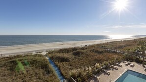 Blick auf einen Strand mit Pool und Liegestühlen.