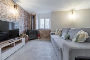 A modern living room with a TV, sofa, fireplace, and stone wall.
