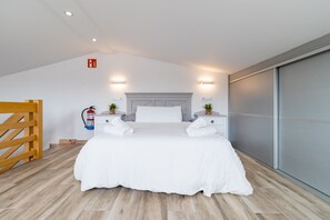 A bedroom with a large bed, bedside tables with lamps, a fire extinguisher, and a sliding door.