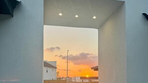 Une porte ouverte donnant sur un parking avec vue sur le coucher de soleil.
