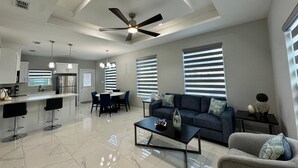 Un salon moderne comprenant un coin repas, une cuisine et un ventilateur de plafond.