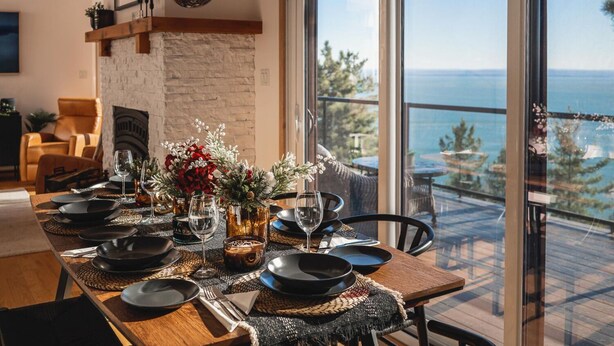 Een eetgedeelte met een tafel voor vier personen, een open haard en uitzicht op zee.