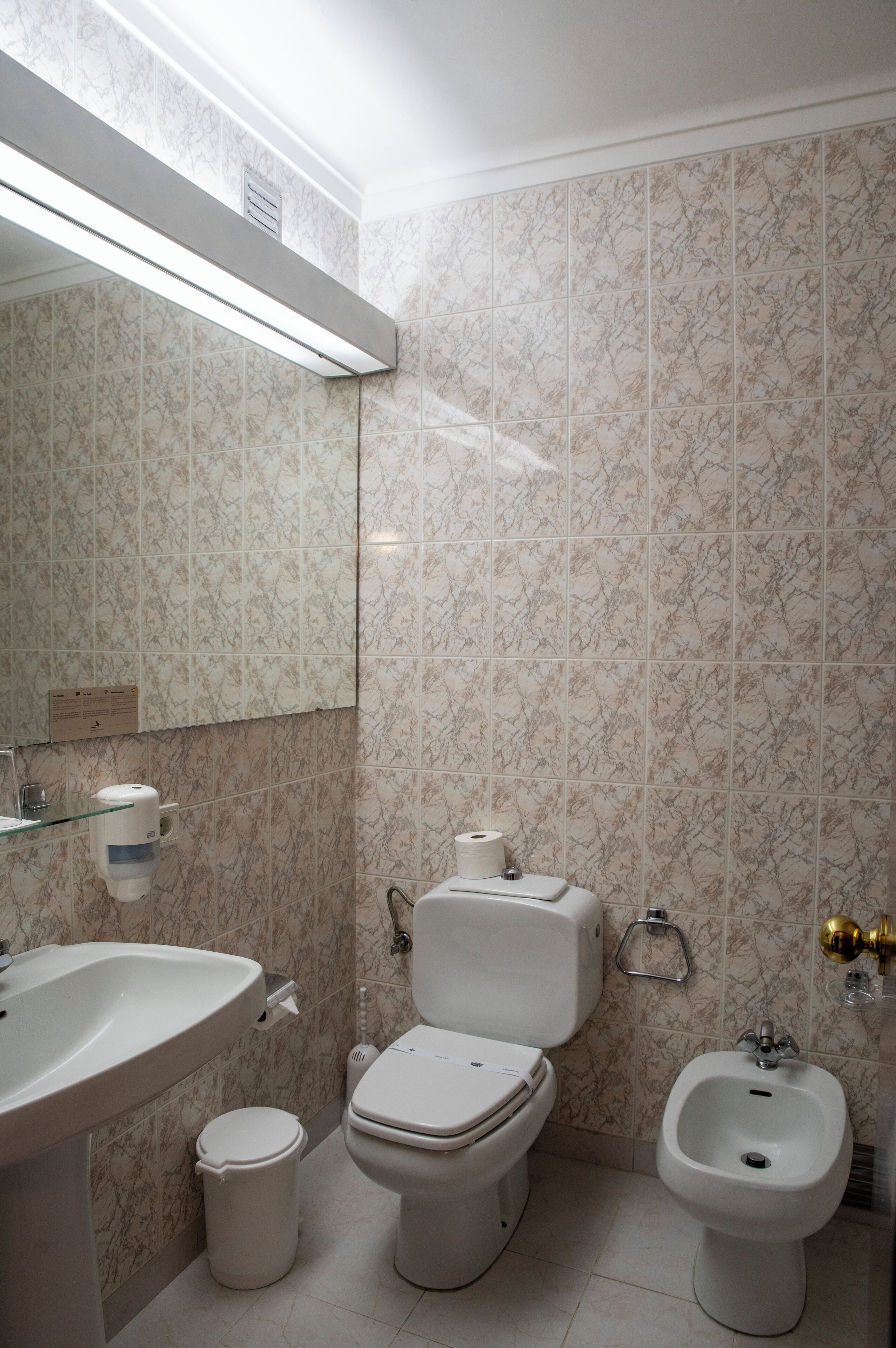 A bathroom with a toilet, bidet, and sink.