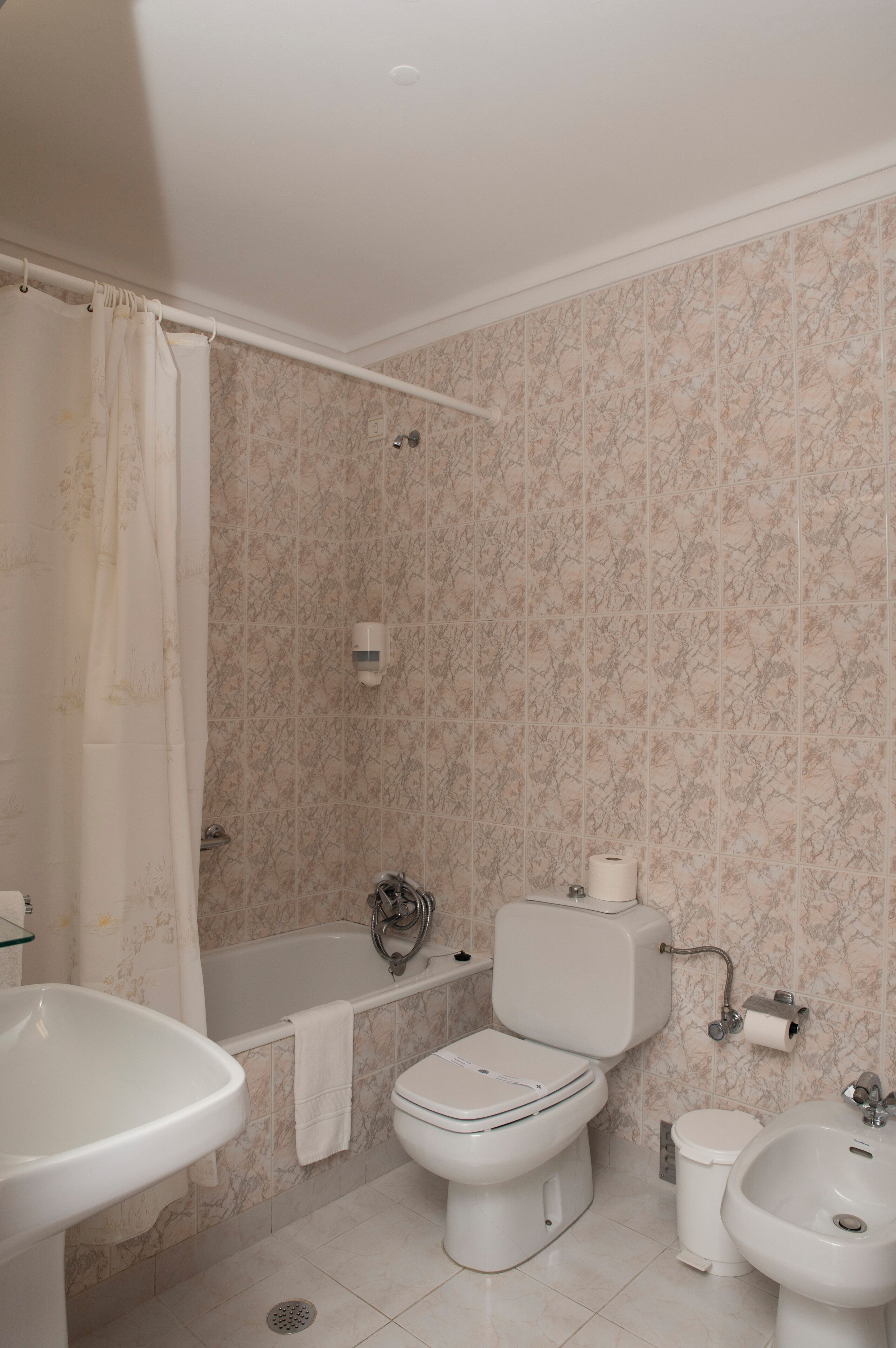 A bathroom with a bathtub, toilet, sink, and bidet.