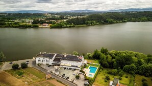 An aerial view of a large hotel with a swimming pool, surrounded by lush greenery and a lake. - WOT Pateira Soul (Agueda)