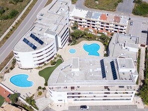 Moderni hotelli, jossa on useita uima-altaita, kattopuutarha ja pysäköintialue.