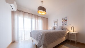 A bedroom with a bed, bedside table, and a wall-mounted lamp.