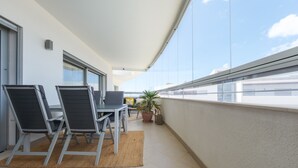A balcony with a table and chairs, a potted plant, and a view of the city.