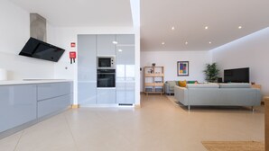 A modern kitchen with built-in appliances and a dining area with a sofa and TV.