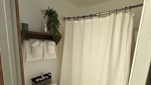 A small, compact bathroom with a toilet, a shelf with toiletries, and a shower curtain. - 113 -The Sandlot- King Suite & Silver Dollar City Gem! (Branson)