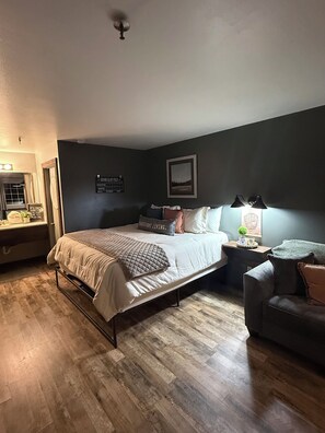 A bedroom with a bed, bedside tables, a chair, and a wall-mounted lamp.