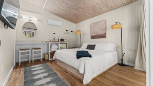 Ein Schlafzimmer mit Bett, Nachttisch, Lampe und Schreibtisch mit Stuhl.