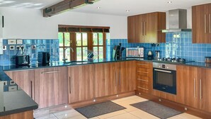 A modern kitchen with wooden cabinets, a black countertop, and a built-in oven.