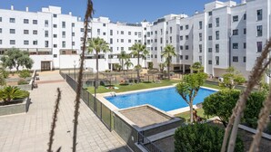 Un edificio moderno con piscina, rodeado de follaje y palmeras.