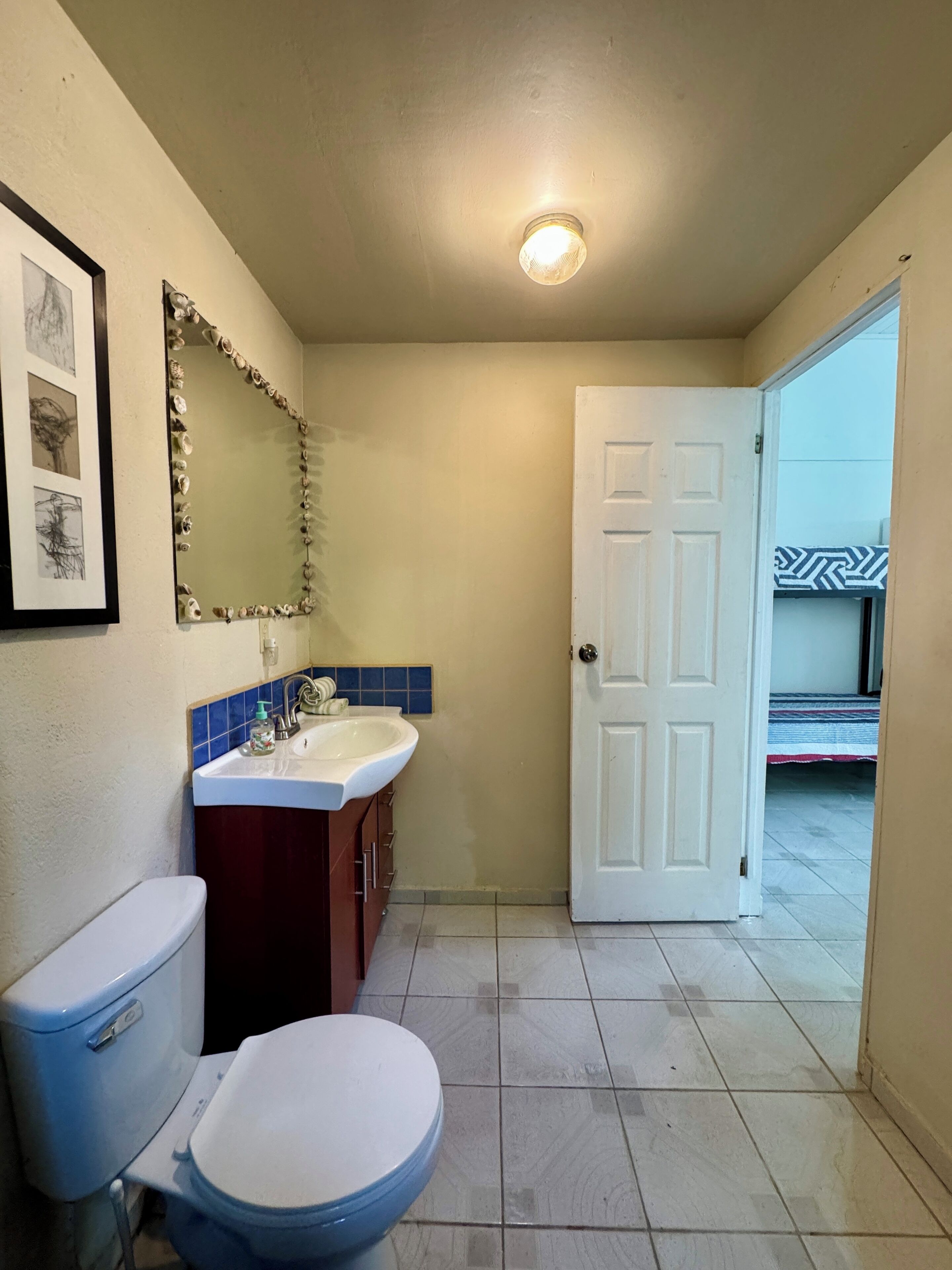 A bathroom with a toilet, sink, and mirror.