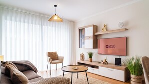 Un salon moderne comprenant un canapé, un fauteuil, une table basse, un téléviseur et des objets décoratifs.