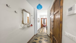 A hallway with a geometric patterned floor, a large mirror, and a blue pendant light. - Historical Apartment in the heart of Lucca (Lucca)
