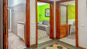 A hallway with a radiator, a patterned rug, and a green wall with a painting. - Historical Apartment in the heart of Lucca (Lucca)