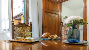 A wooden table with a tray of pastries, a vase with flowers, and a door with a traditional design. - Historical Apartment in the heart of Lucca (Lucca)