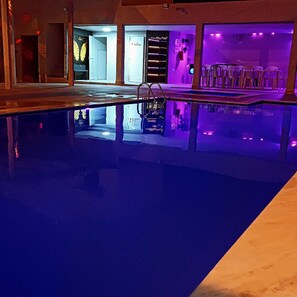 A swimming pool with a metal ladder, surrounded by a building with purple lighting. - Country house in Arcoverde/PE for accommodation, season and São João. (Arcoverde)