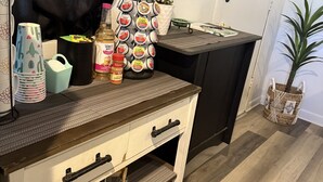 A kitchen counter with a coffee maker, a spice rack, and a 'No Pricks Allowed' sign.
