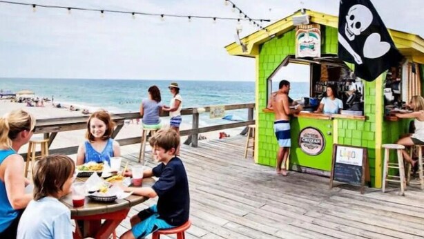 Een restaurant aan het strand met terras en uitzicht op de oceaan.