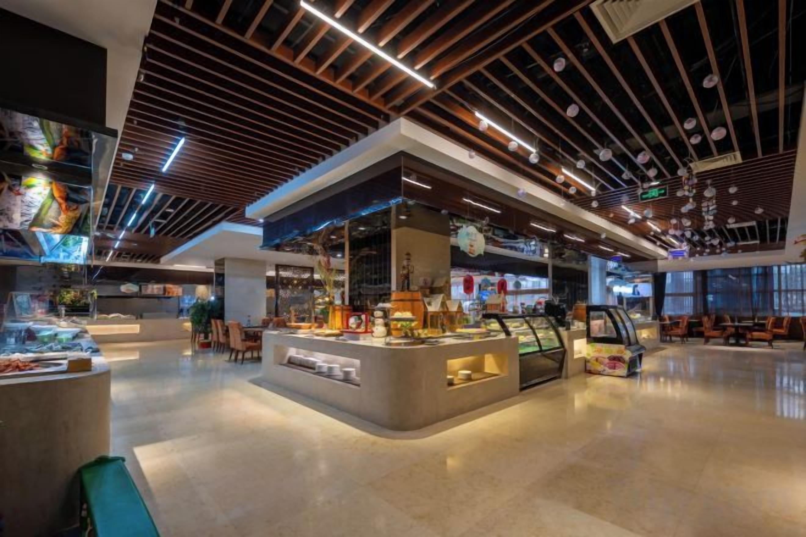 A modern interior with a central counter, seating areas, and a ceiling with linear lighting.