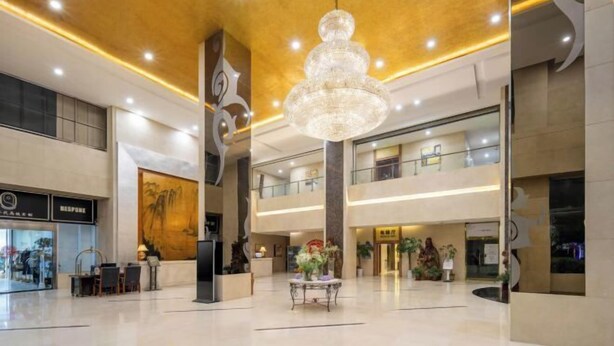 Un vestíbulo amplio con un candelabro, una recepción y un mural en la pared.