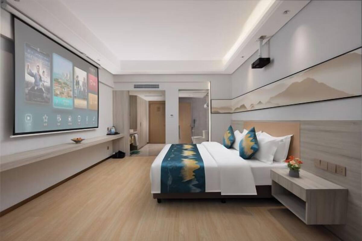 A modern hotel room with a large bed, a TV screen, and a minimalist design.