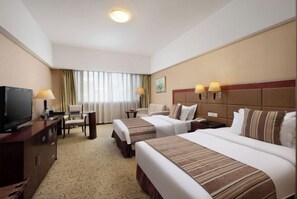 A hotel room with two beds, a TV, a desk with a chair, a lamp, and a painting on the wall. - Qingdao West Coast City Terrace Detai Hotel (Qingdao)