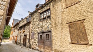 Eine enge Gasse mit Steinbauten, Holztüren und Fensterläden.