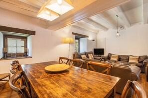 Un espace repas comprenant une table et des chaises en bois, un canapé, un téléviseur et une lampe.