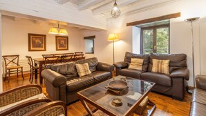 Ein Wohnzimmer mit Ledersofas, einem Glastisch, Holzstühlen und einem Essbereich mit Tisch und Stühlen.