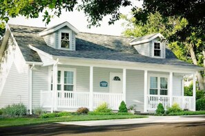 A two-story white house with a front porch, a small attached garage, and a sign indicating it is a bed and breakfast. - Cottage with jacuzzi, Downtown Berlin Ohio (Berlin)