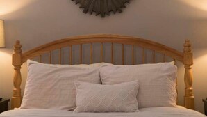 A bedroom with a wooden headboard, a round wall decoration, and two bedside lamps. - Cottage with jacuzzi, Downtown Berlin Ohio (Berlin)