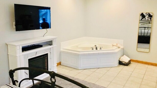 Une salle de bain moderne avec une grande baignoire, un téléviseur fixé au mur et un miroir.
