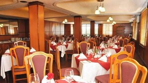 A restaurant with multiple tables set for dining, featuring wooden chairs and red tablecloths. - Jarika Watamu Breeze Hotel (Nakuru)