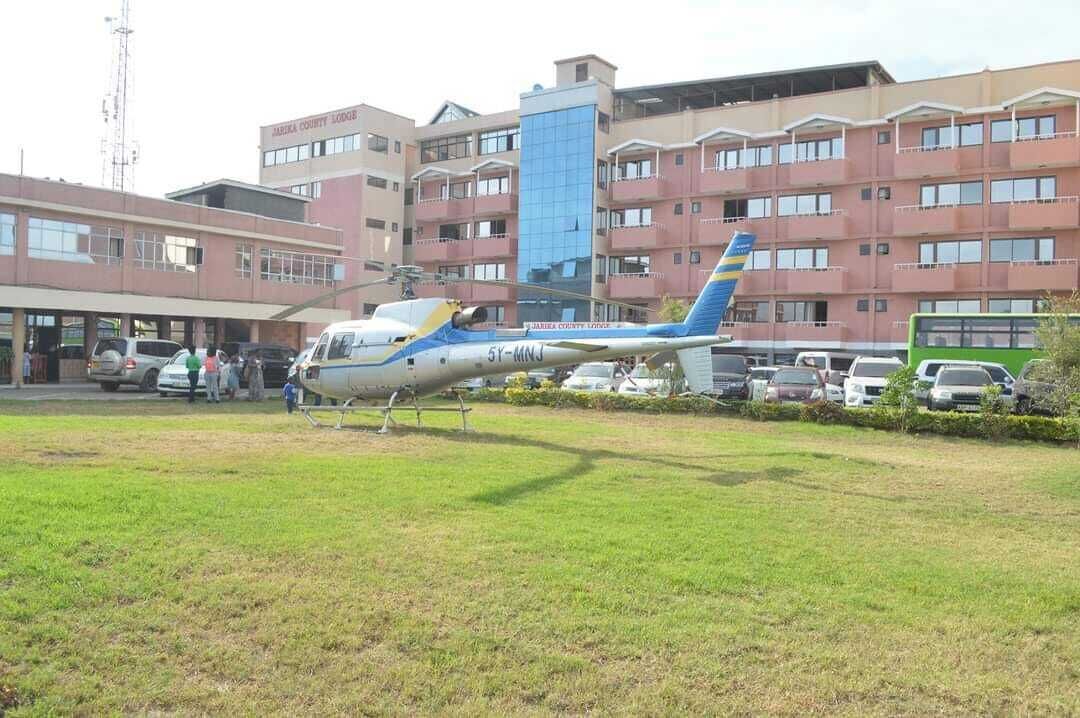 A helicopter parked in front of a building with multiple windows and balconies.