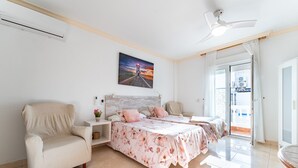 Un dormitorio con dos camas, una silla, una mesita de noche y un cuadro en la pared.