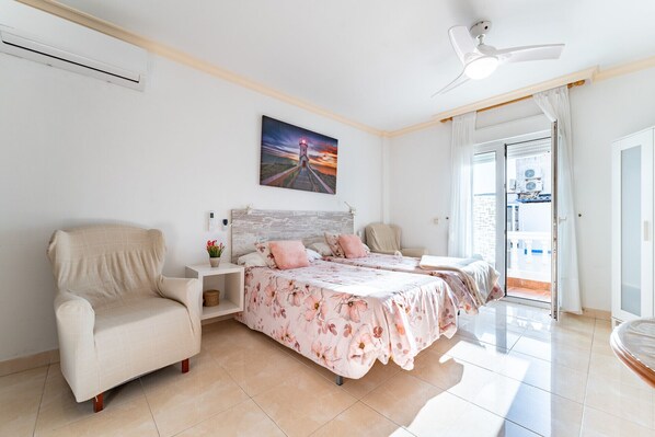 A bedroom with two beds, a chair, a nightstand, and a painting on the wall.