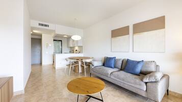 A modern living room with a grey sofa, round coffee table, and a dining area with a round table and chairs.