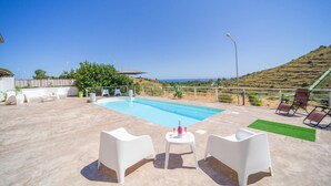 A pool area with a clear view of the sea, surrounded by white furniture and a small table with drinks. - Gorgeous home in Trabia (Trabia)