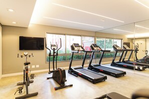 Un gimnasio con cintas de correr, elíptica y bicicleta estática.