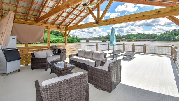 An outdoor deck with wicker furniture, a grill, and a view of a river. - Bridge View Retreat, Bridge View Retreat- Luxurious 4Br -Lake Martin Home (Alexander City)