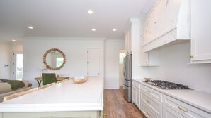 A spacious kitchen with white cabinetry, a large island, and a stainless steel refrigerator. - Bridge View Retreat, Bridge View Retreat- Luxurious 4Br -Lake Martin Home (Alexander City)
