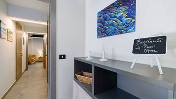 Un couloir avec un comptoir d’accueil, un tableau représentant des poissons accroché au mur et un panneau noir.