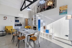 Ein modernes Interieur mit Essbereich, gelbem Sessel, Treppe und Kunstwerken an den Wänden.