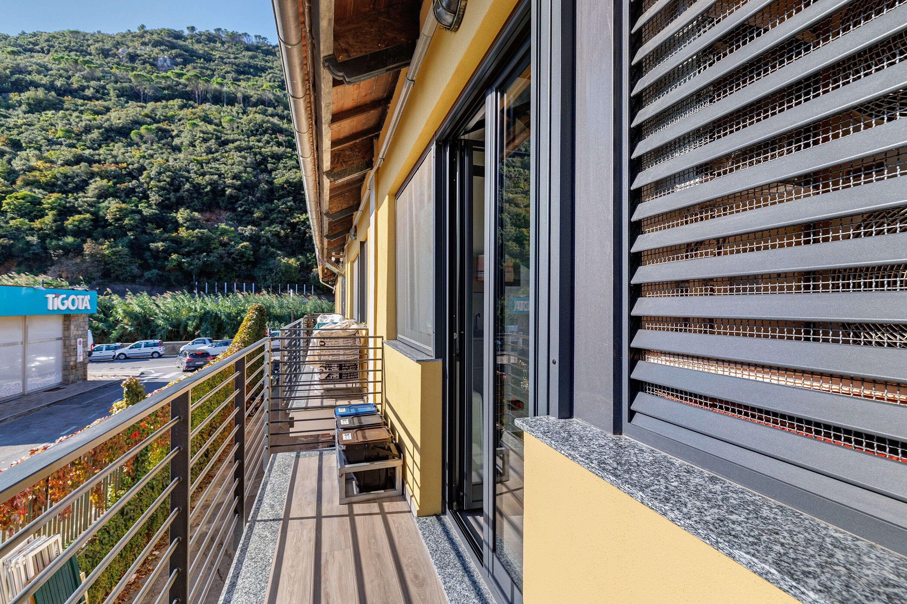 Un balcon donnant sur une colline boisée, un bâtiment à la façade jaune et une enseigne sur laquelle on peut lire « TOUR ».