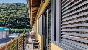 Un balcón con vista a una colina arbolada, un edificio de fachada amarilla y un letrero que dice 'TOUR'.