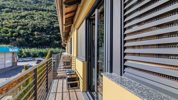 Un balcon donnant sur une colline boisée, un bâtiment à la façade jaune et une enseigne sur laquelle on peut lire « TOUR ».